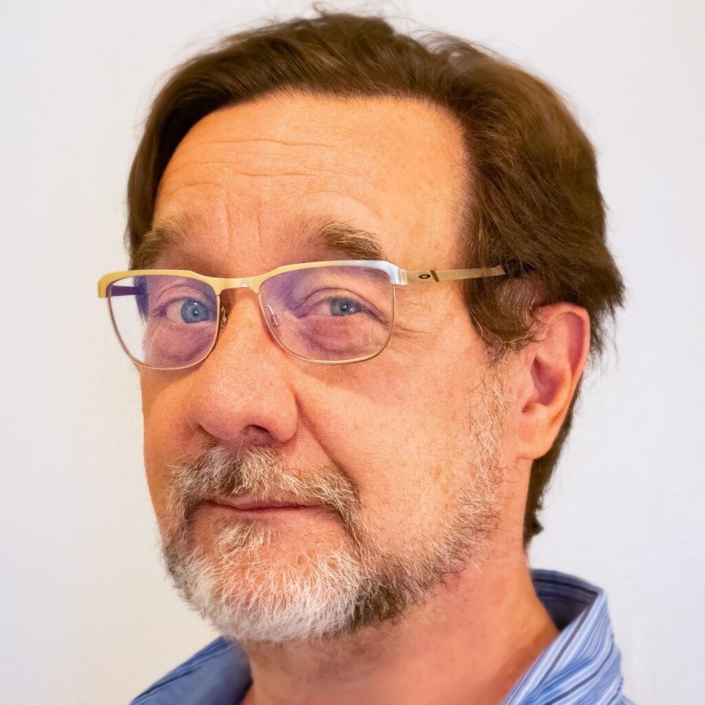 Middle-aged white guy with brown hair, blue eyes, grey beard, and glasses.